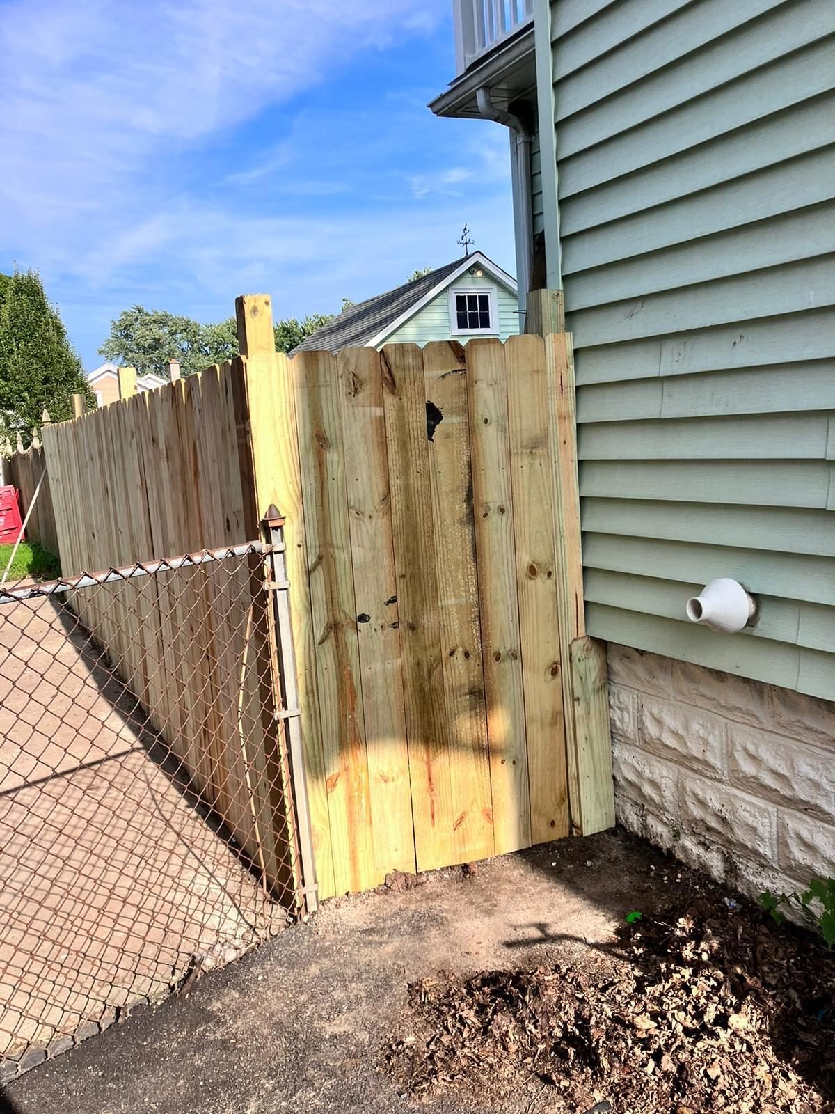 New wood fence gate installed beside an existing chain link fence