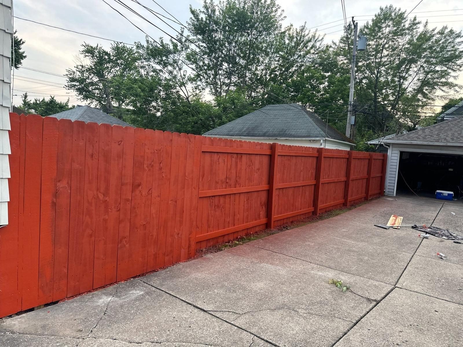 Fence staining and sealing project finished in a red barn stain