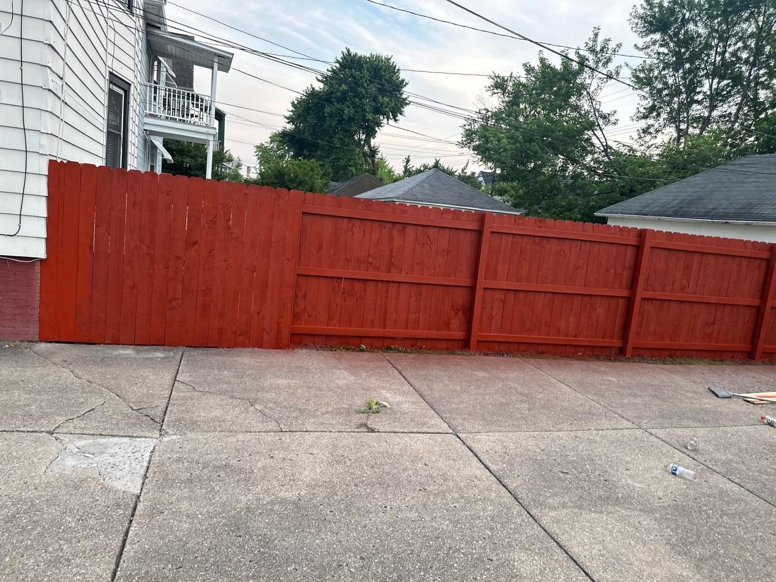 Stained privacy fence along a long driveway run