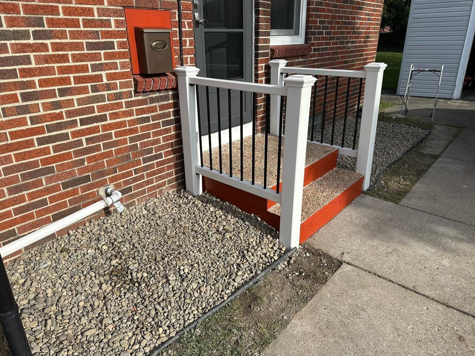 Porch step repair with red painted stairs on a brick home