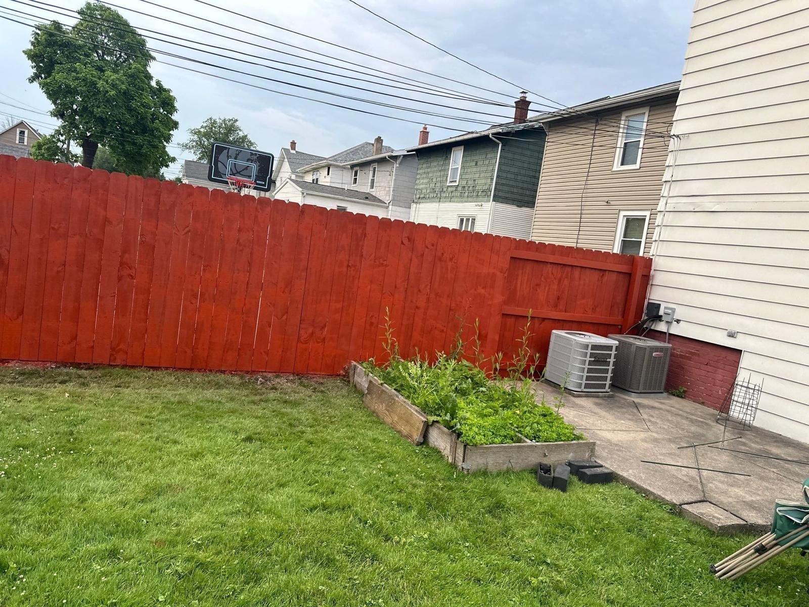 Red stained privacy fence enclosing a backyard