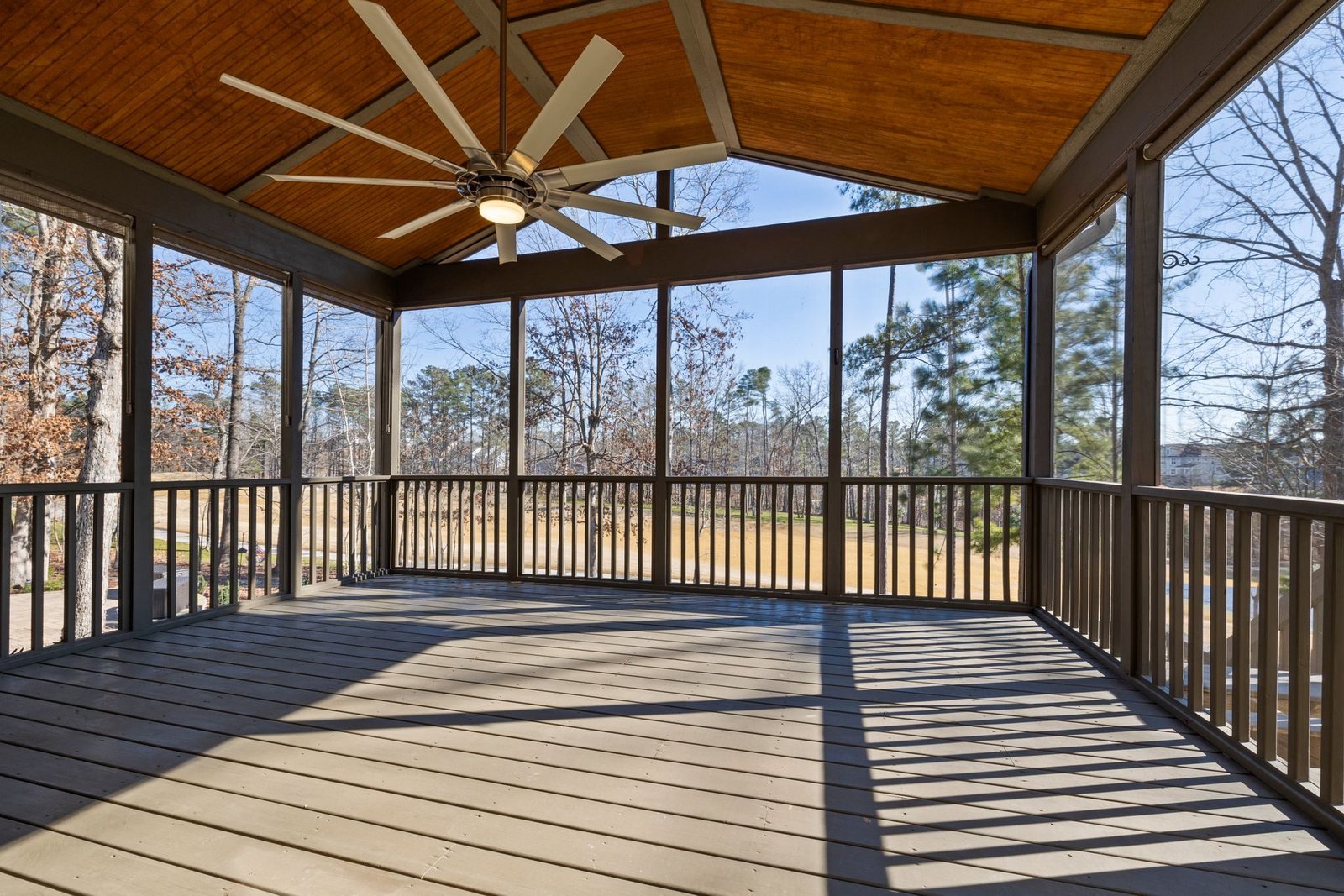 Screened in porch with wood ceiling fan and deck flooring