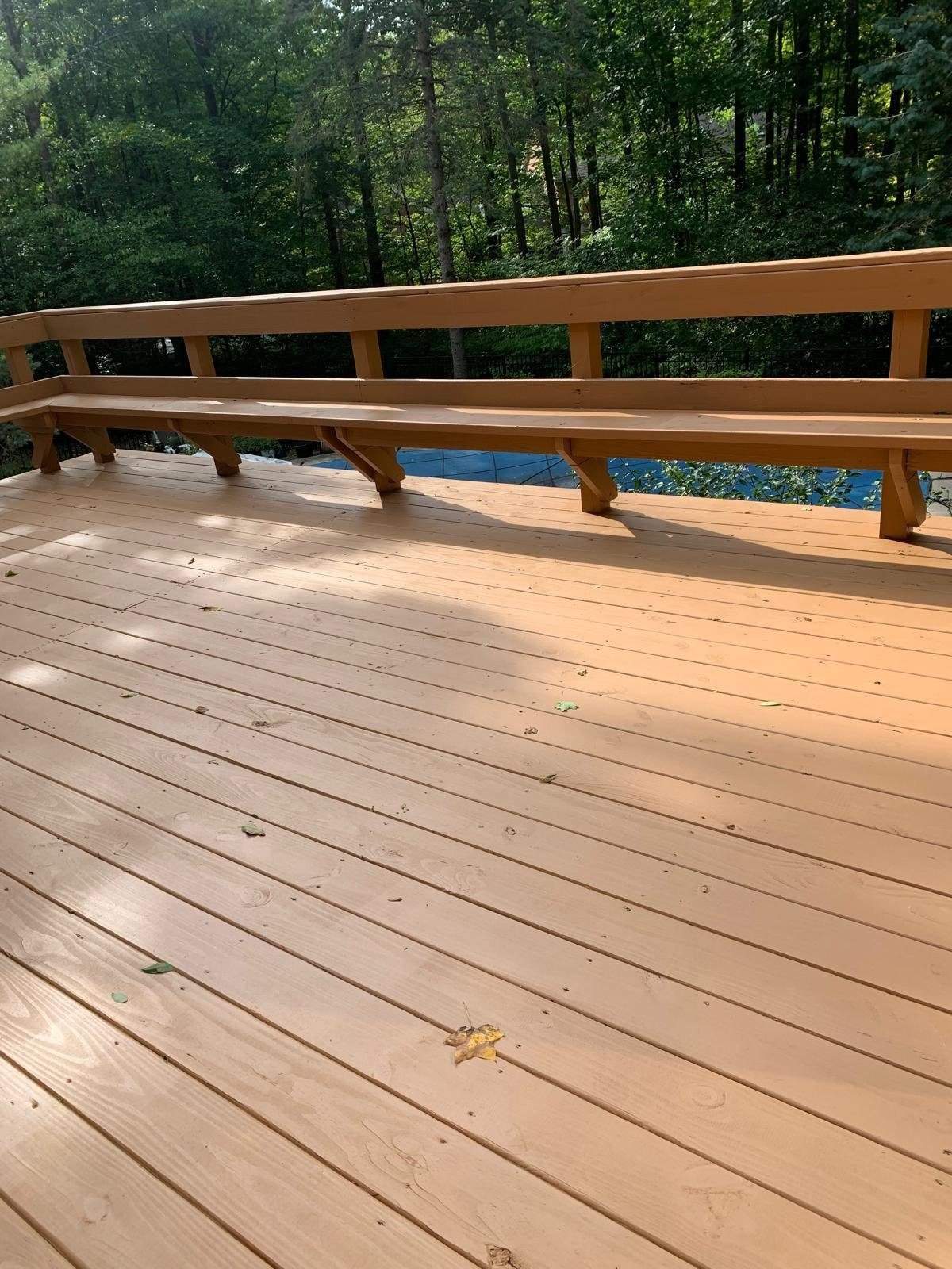 Freshly stained deck with built-in bench overlooking a pool