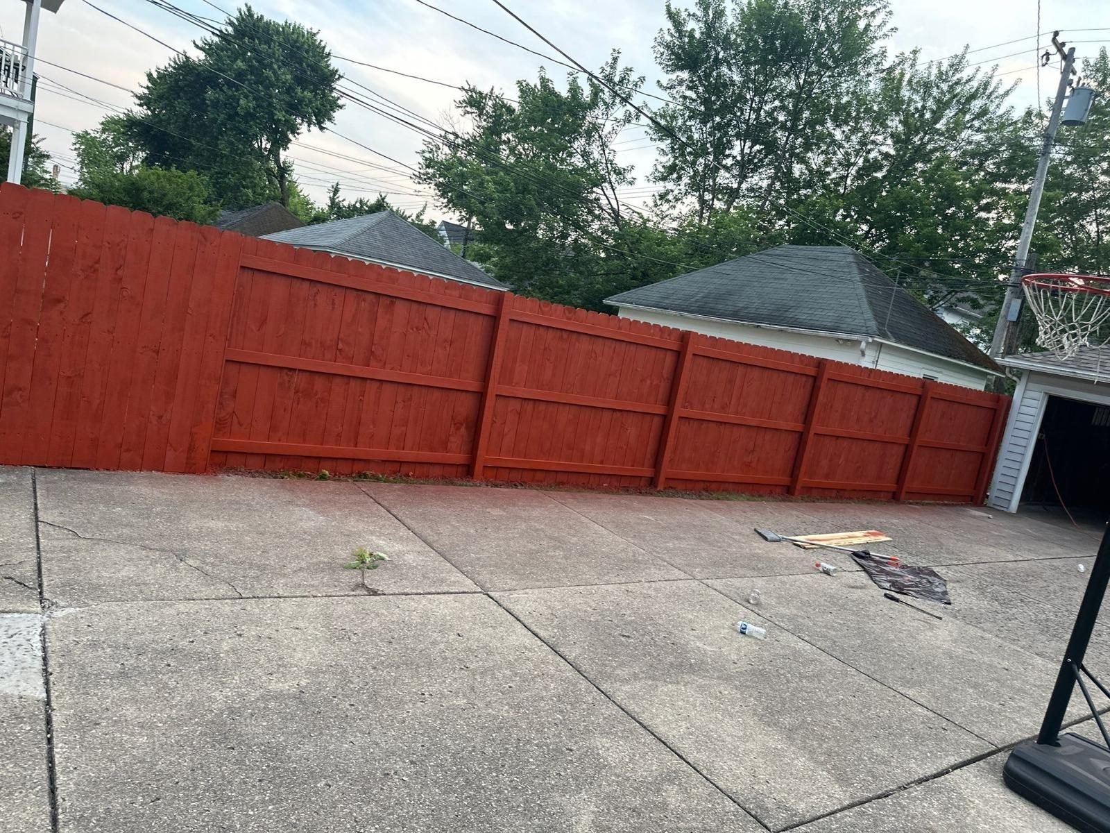 Freshly stained wood fence panels along a driveway